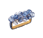 The Kim Seybert Pop Rocks Napkin Ring features a rectangular gold band adorned with clustered faceted blue gemstones for a sparkling, bejeweled look.