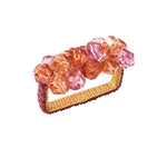 The Kim Seybert Pop Rocks Napkin Ring features a gold rectangular shape adorned with clusters of faceted orange and pink gems, creating a sparkling, bejeweled effect.