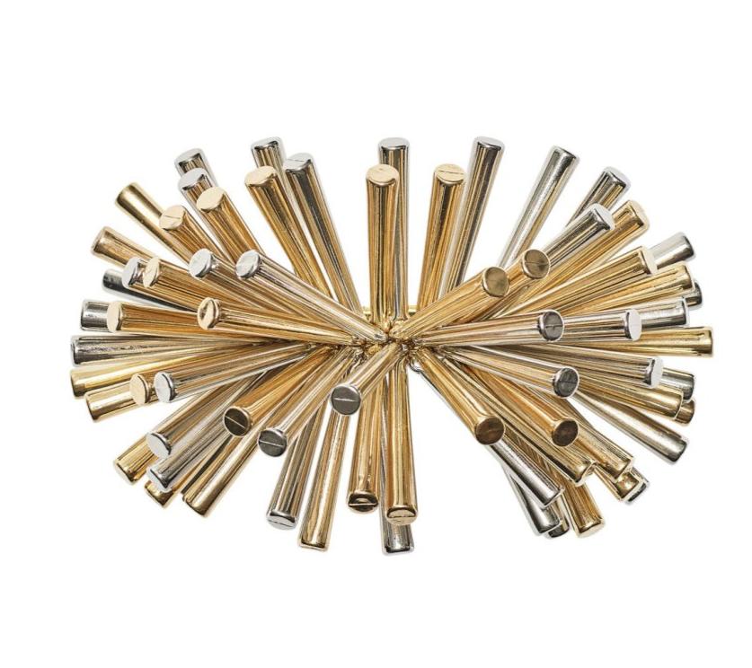 The Kim Seybert Fringe Napkin Ring is a decorative metallic accessory with gold and silver rods and metal beads radiating from the center, adding a glamorous touch to your table setting.