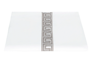 A folded white sheet from Matouk’s Ophelia Bedding Collection, Mocha, features a vertical Greek key trim in gray and black along the center and is crafted with a luxurious 520 thread count.