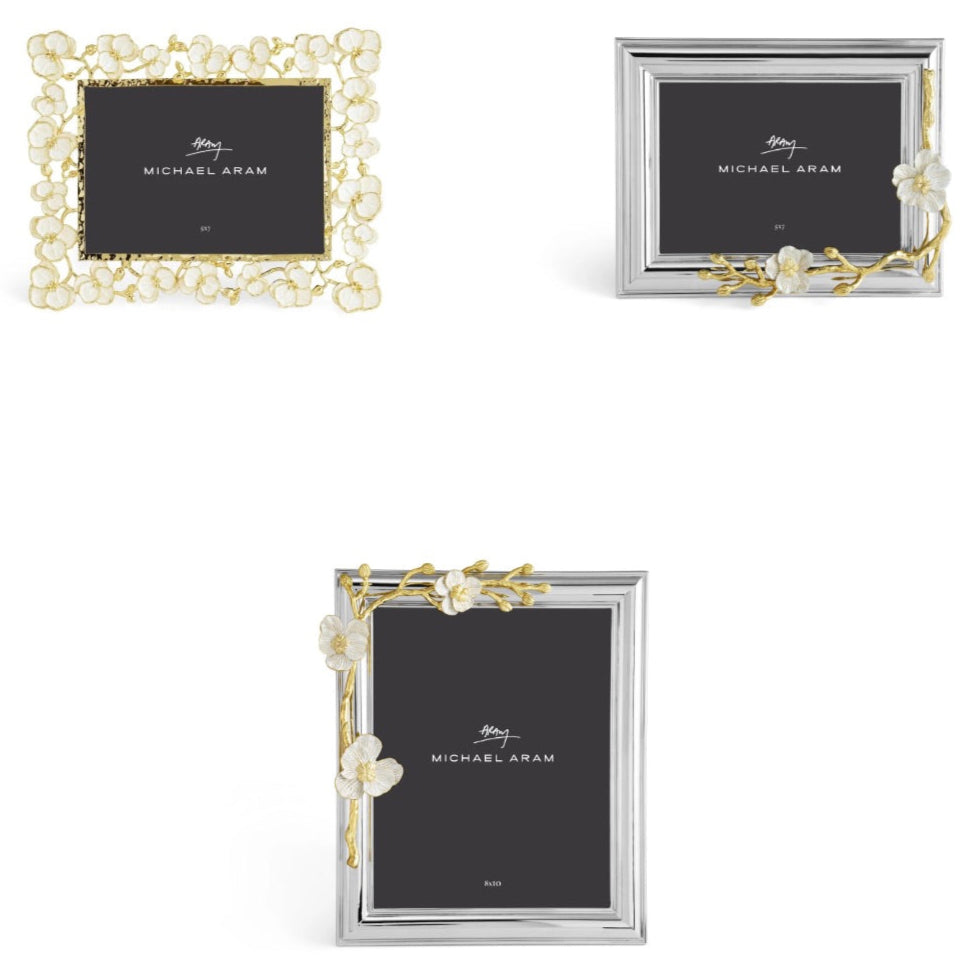 Three rectangular photo frames from the Michael Aram Orchid Frame Collection feature elegant floral designs in golden brass and silver finishes, displayed on a white background.