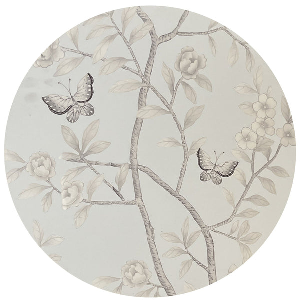 Round ceramic plate featuring a delicate, monochromatic floral and butterfly design in a gray palette with a Tisch Chinoiserie Coaster Collection by Tisch NY.