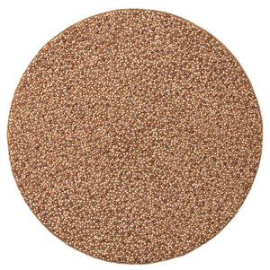 A round pile of small, tan to light brown grains rests on the Kim Seybert Emberfall Placemat, viewed from above against a white background.