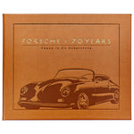 A leather-bound book cover by Graphic Image, titled "Porsche 70 Years: There is No Substitute," featuring a vintage Porsche illustration and chronicling automotive history as detailed by Randy Leffingwell.