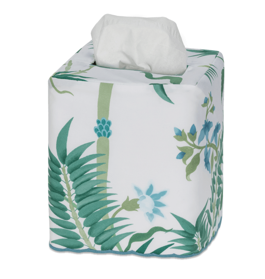 The Matouk Palmyra Tissue Box Cover in Emerald features a green leaf and blue flower pattern, bringing an island-inspired touch to your decor as it neatly covers a square tissue box with a white tissue popping out from the top.