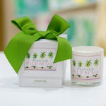 The Perfectly Palm Beach Signature Scent Collection includes a white candle and matching box with palm tree designs, a green bow, and the brand's signature fragrance inspired by Palm Beach.