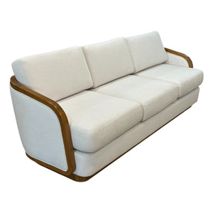 The Schooner Sofa in Outdoor Ivory Chenille by McGuire Furniture is a three-seater with curved wooden armrests and frame, upholstered in light beige for a natural, coastal-inspired look.