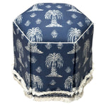 Experience comfort and style with the Evans Skirted Ottoman by Highland House—a hexagonal blue ottoman featuring custom fabric, white palm tree patterns, white piping, and a fringed base trim.