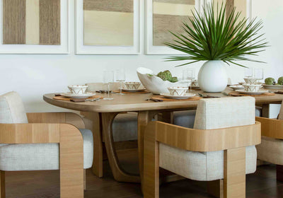 contemporary dining vignette with light wood colored dining chairs, light wood table with neutral table settings, and a green spiky plant on table