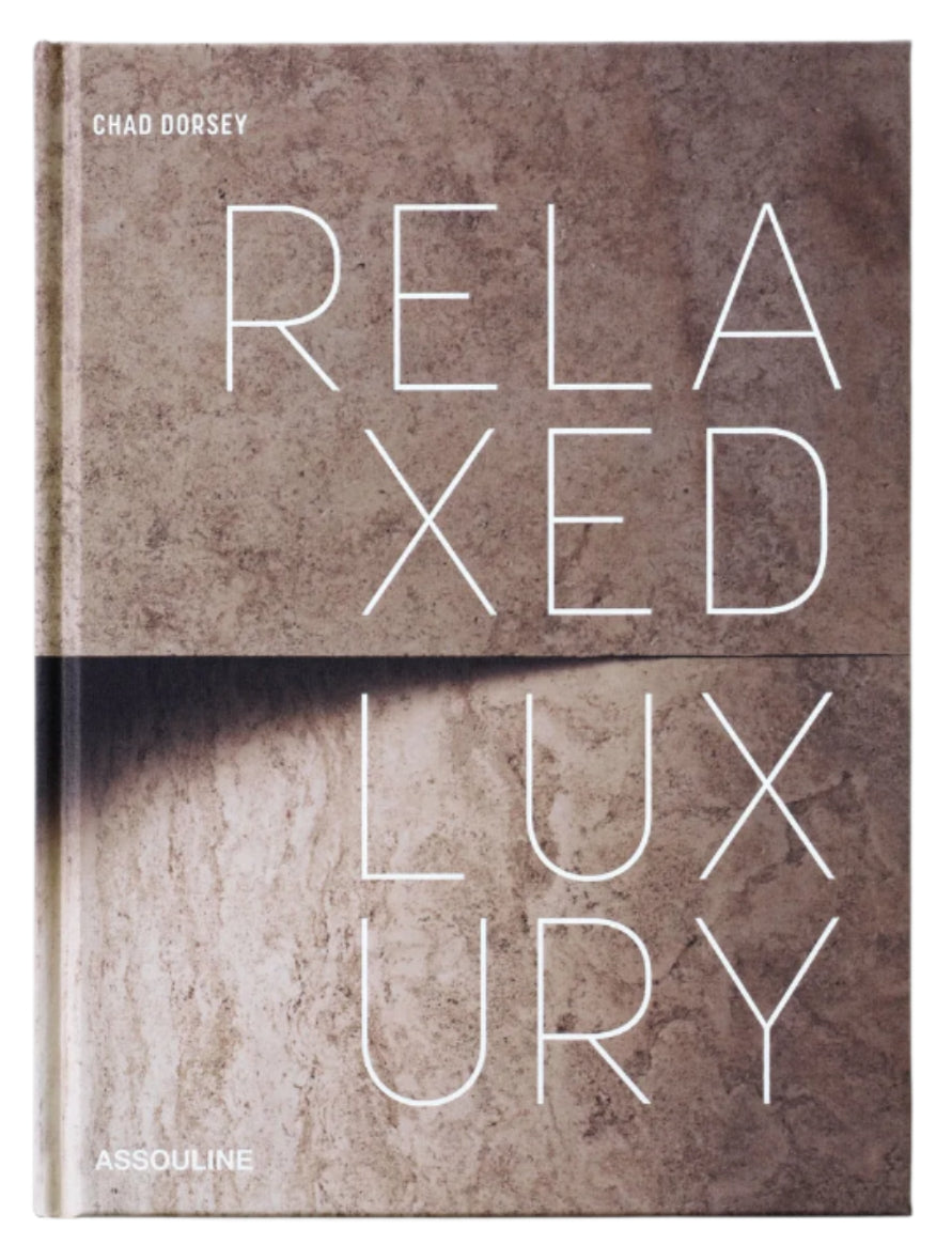 The cover of Assouline’s "Relaxed Luxury" features bold white lettering on a textured beige stone backdrop, mirroring the book’s sophisticated take on interior design.