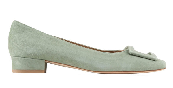 Green Ann Mashburn suede flat shoe with a decorative bow on the toe, isolated on a white background.