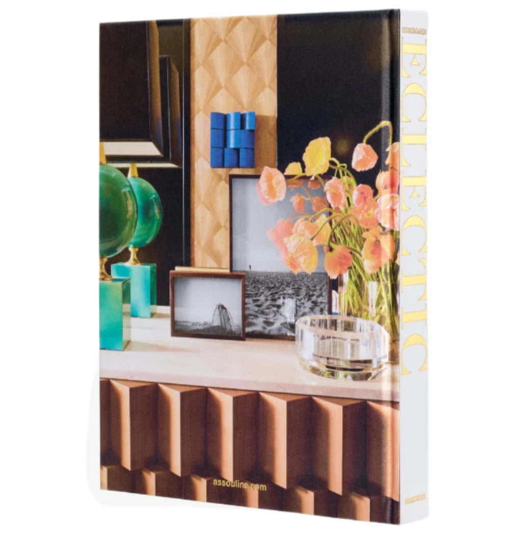 The book "Sig Bergamin Eclectic" by Assouline, featuring a cover with vibrant decor elements like glass spheres, flowers, and framed art, encapsulates Sig Bergamin's creative design and eclectic interiors.