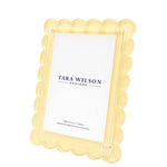 Brighten your decor with this yellow scalloped-edge photo frame from Tara Wilson Designs’ Scallop Frame Collection, featuring a clear front and a "Tara Wilson Designs" placeholder card. A cheerful best-seller for any space.