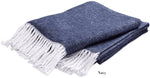 The Matouk Pezzo Throw Collection features a folded navy blue cozy throw with white fringed edges, crafted from brushed cotton and displayed against a white background. "Navy" appears near the blanket.