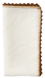 The Kim Seybert Knotted Edge Napkin Set features neatly folded white 100% linen napkins with brown decorative stitching, a hand-crocheted textured border, and elegant edging.