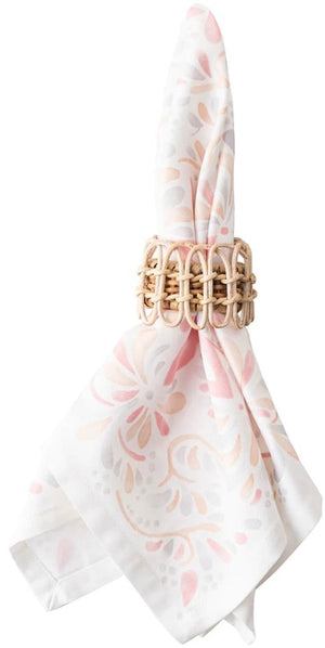 Juliska’s Provence Napkin Ring, hand-woven from rattan, elegantly secures a white napkin featuring a subtle pink and beige floral pattern—perfect for enhancing your table setting.