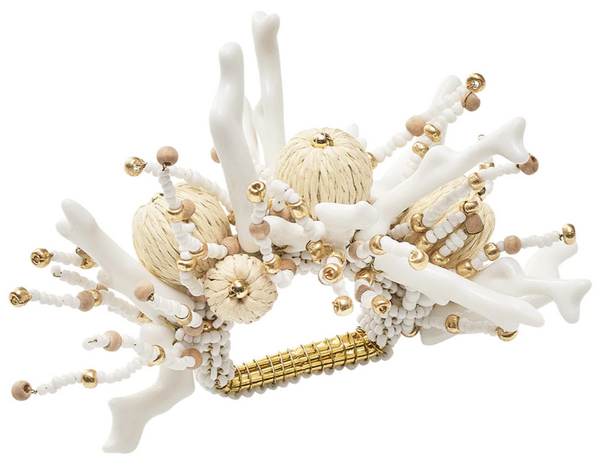 A white and gold Kim Seybert Coral Spray Napkin Ring Collection with shells and pearls, reminiscent of a beach vacation.
