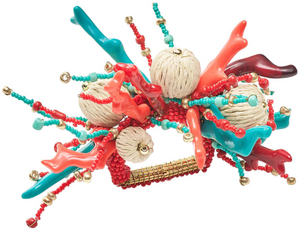 The Coral Spray Napkin Ring by Kim Seybert features red and turquoise coral-inspired pieces, gold beads, and cream rope balls on a gold base, adding an elegant touch to your table.