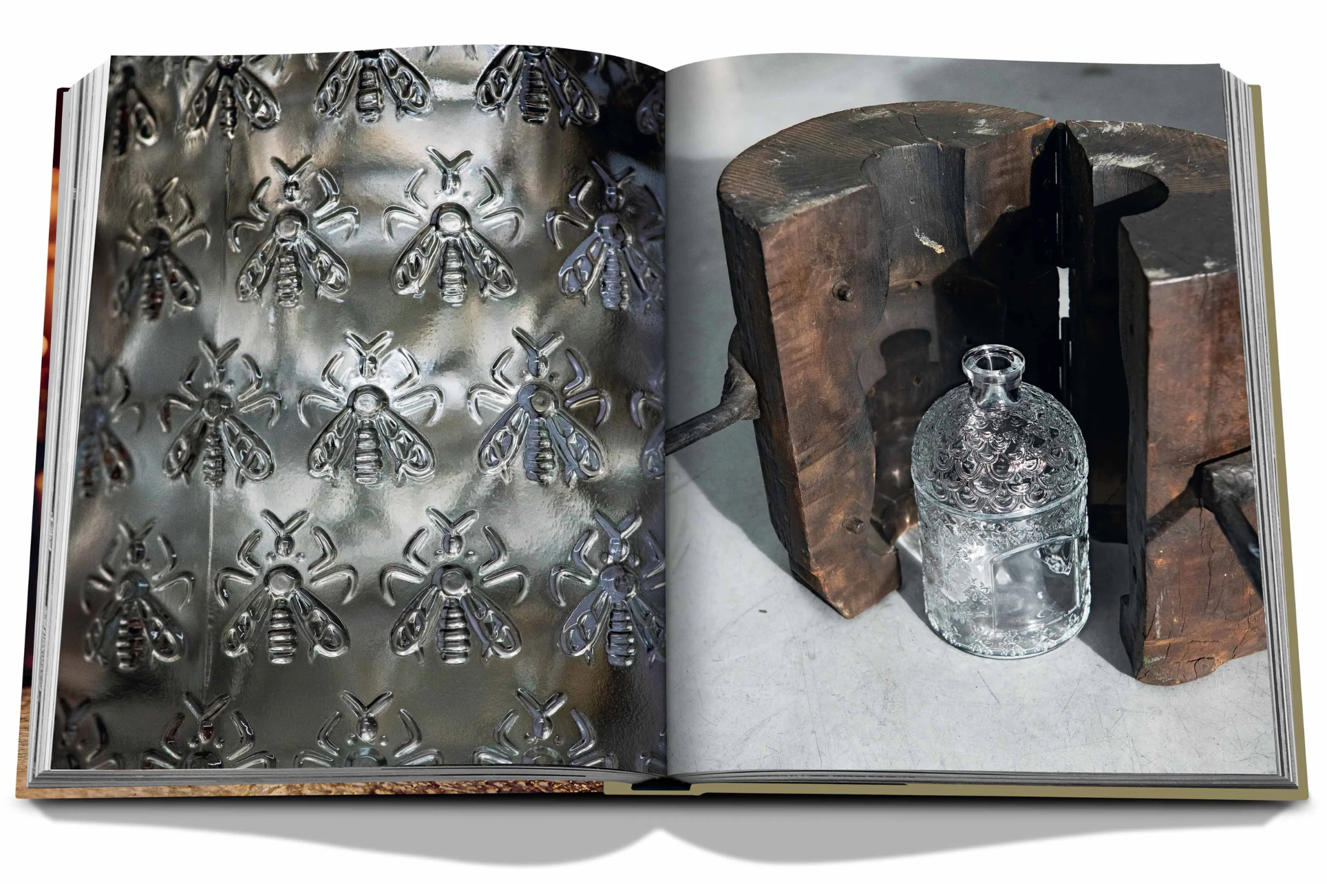 An open book reveals a patterned metallic surface adorned with bee designs on the left page while the right showcases an Assouline jar of Guerlain An Imperial Icon, intricately detailed, beside a wooden block.