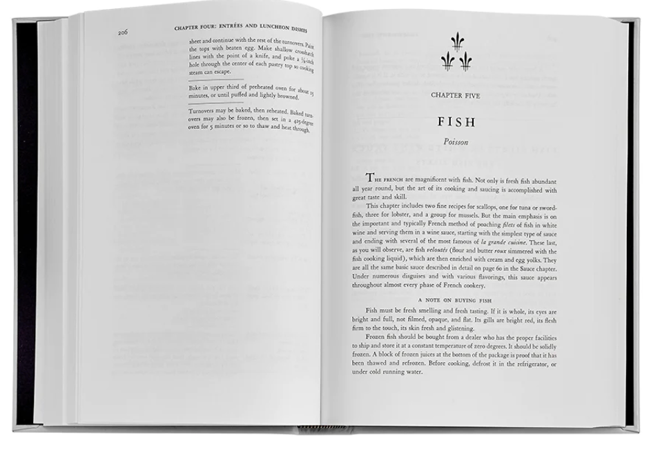 An open book reveals Chapter Five, "Fish," from the esteemed cookbook "Mastering the Art of French Cooking Leather" by Graphic Image, with text elaborating on the significance and preparation of fish dishes.