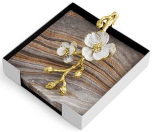 The Michael Aram Orchid Cocktail Napkin Holder, with its wooden texture and gold-and-white flower accent, embodies subtle luxury and celebrates delicate nature.