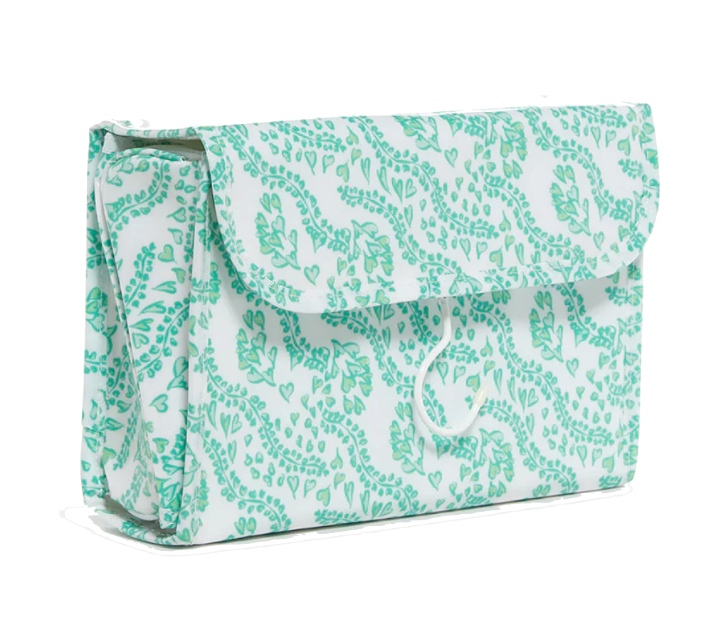 The TRVL Design Luxe Gloss All Heart Travel Set in Kelly Green is a rectangular fabric cosmetic bag with a botanical print and flap closure, shown on a white background—ideal for organizing your travel accessories.