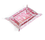 The Luxe Gloss All Heart Travel Set in Kelly Pink by TRVL Design features a rectangular pink tray with heart motifs, raised sides, and folded, buttoned corners—ideal for travel accessories. A smaller matching tray nests inside.