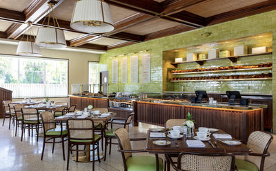 interior of hive bakery and cafe with green tiled walls, wood paneled counter, and green and cane-backed dining chairs