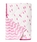 The Averylily Surfer Bedding Collection features a folded white quilt in soft cotton voile with pink bird prints inspired by artisanal block printing on one side, pink wavy lines on the other, and finished with pink trim.
