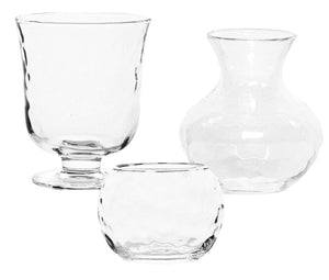 Three empty vases from the Juliska Puro Clear Glass Vase/Votive Collection, each with a contemporary silhouette and varying shapes and sizes, are displayed against a white background.