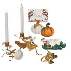 The Forest Walk Tabletop Collection by Juliska features gold candle holders with white candles, white and orange pumpkins, and "Ryder" and "Fern" place cards with whimsical mushroom and flower details for an elegant tablescape.