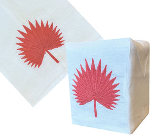 The Haute Home Palm Leaf Bath Collection in Coral features a white Italian linen napkin with a red, hand-embroidered palm leaf design, shown flat and folded into a rectangle.