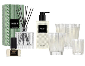 The Nest Birchwood Pine Collection offers a winter forest scent with a reed diffuser, liquid soap, perfume spray, and four holiday candles, all beautifully showcased against a white background.