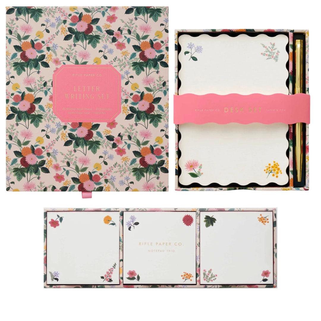 The Riffle Paper Co. Dahlia Collection features floral-themed stationery sets with letter writing paper, envelopes, and desk accessories, all elegantly arranged in decorative boxes.
