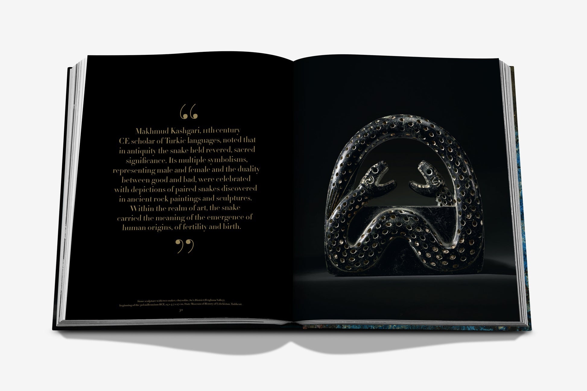Assouline's 'Uzbekistan: Masterpieces of the Silk Road' presents an open book with black pages that captures a quote about the historical symbolism of fertility and birth. On the right page, a metallic sculpture featuring two snake-like figures is showcased, echoing the rich tapestry of discoveries along the ancient Silk Road and reminiscent of archaeological finds in Uzbekistan.