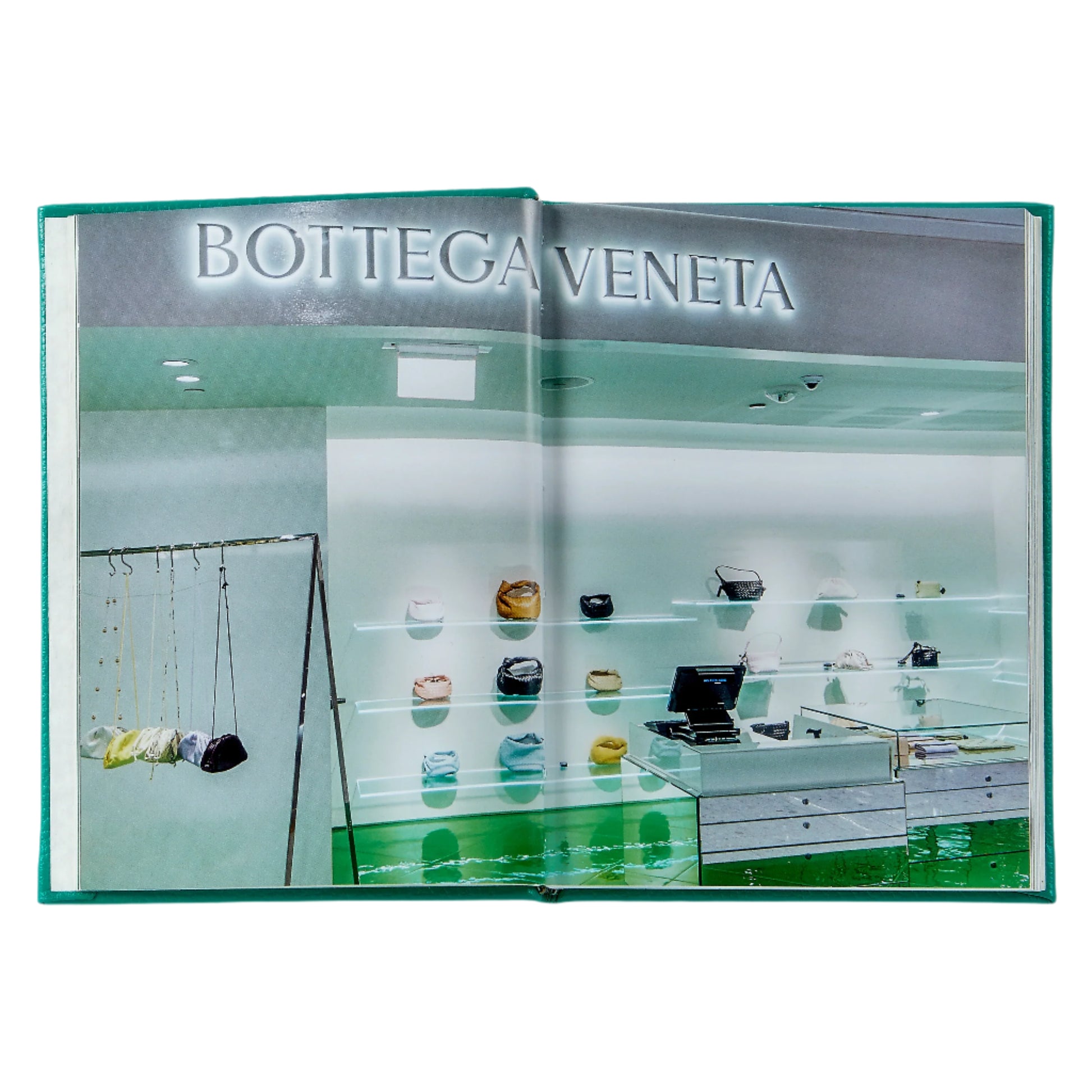 Open to a page in the *Little Book of Bottega Veneta* by Graphic Image, showing signature Intrecciato handbags on wall shelves and in display cases under the glowing luxury brand name.