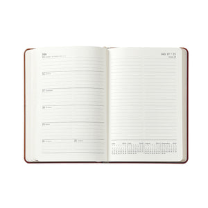 The Graphic Image 2026 Weekly Journal Planner Collection shows a leather notebook open to July 15–21, with lined daily sections and a mini monthly calendar at the bottom right.