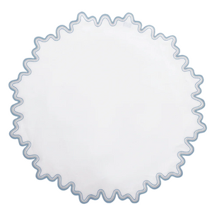 The Matouk Wave Tabletop Collection in Hazy Blue features a round white linen tabletop with a wavy blue embroidered edge and is OEKO-TEX certified for safety and style.
