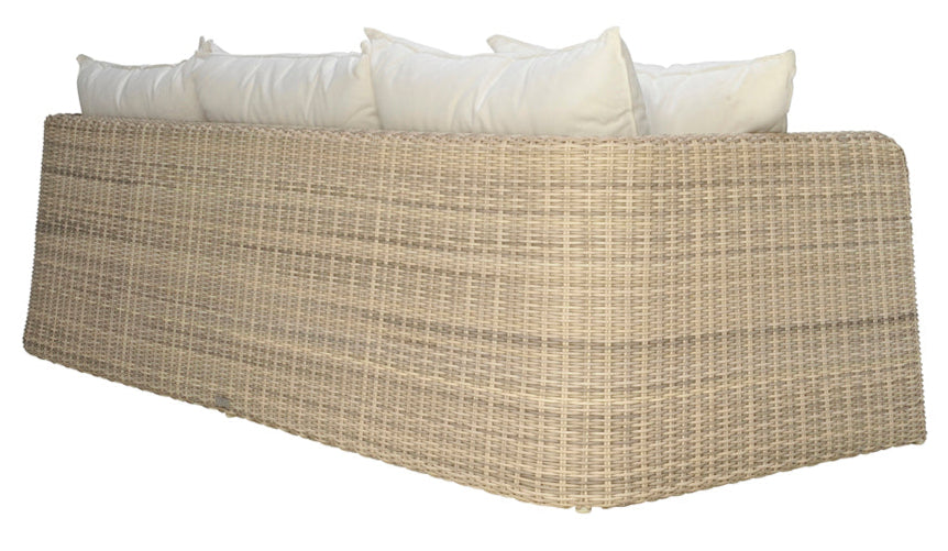 The Zeya Outdoor 3 Seater Sofa by Janus et Cie features beige, weather-resistant wicker and white cushions, shown angled from the back against a white background. This elegant piece brings comfort and style to any patio or garden.