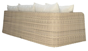 The Zeya Outdoor 3 Seater Sofa by Janus et Cie features beige, weather-resistant wicker and white cushions, shown angled from the back against a white background. This elegant piece brings comfort and style to any patio or garden.