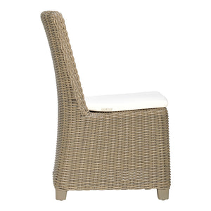 The Zeya Outdoor Dining Side Chair by Janus et Cie features weather-resistant wicker, a high back, and a white seat cushion—perfect for outdoor dining—shown in side view against a plain white background.