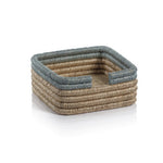 The Zodax La Côte Coiled Napkin Holder Collection features a small, stackable rectangular rattan holder with blue and beige stripes—ideal for coastal table decor, shown on a white background.