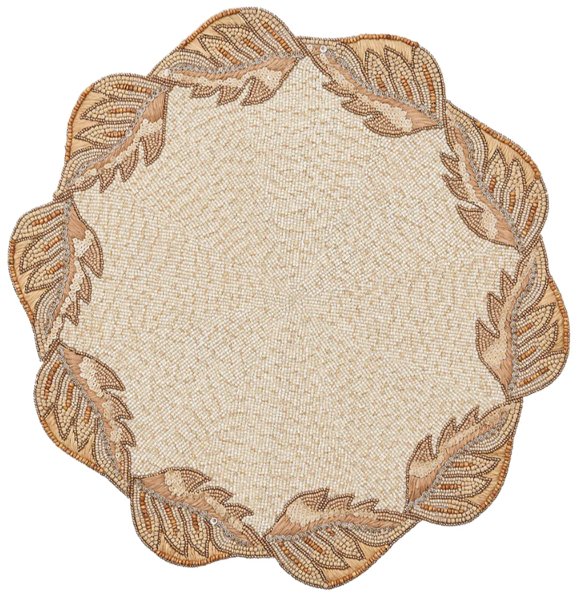 The Kim Seybert Winding Vines Placemat features a round shape, beige and gold tones, scalloped edge, and delicate leaf bead pattern around the border.