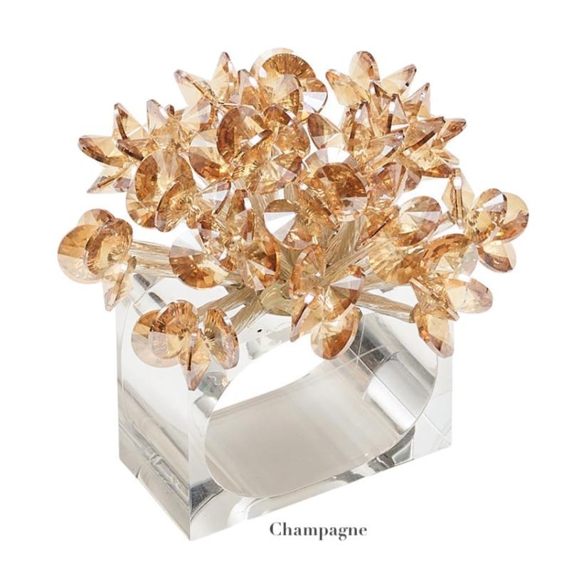 The Kim Seybert Aster Napkin Ring features clear beads and a cluster of faceted champagne-colored acrylic flowers, perfect for elevating your table decor. "Champagne" appears below.