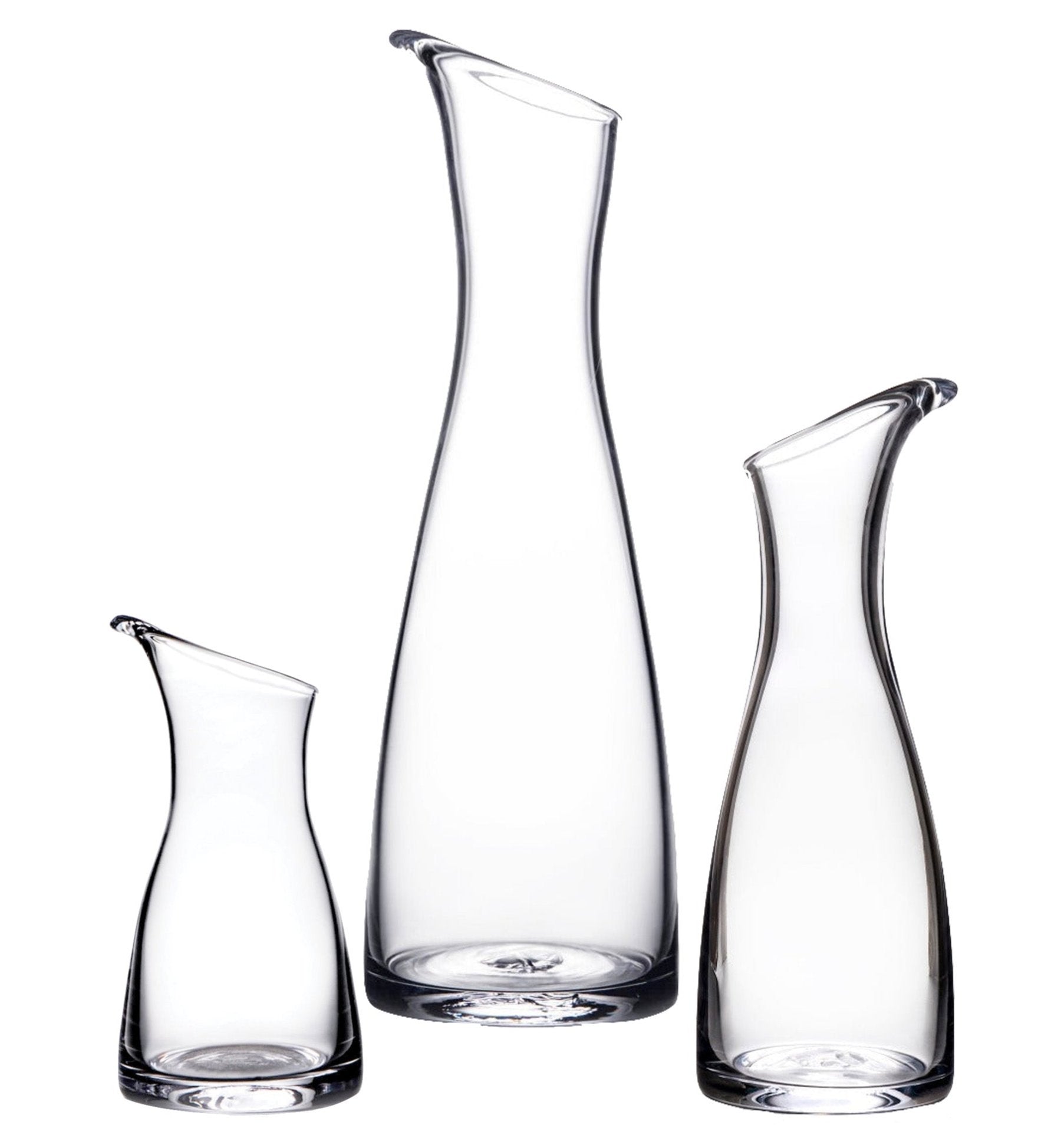 Three upright Barre Carafe Collection vessels by Simon Pearce, in clear handmade glass with slanted rims and varying heights, displayed against a white background.