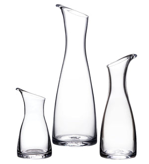 Three upright Barre Carafe Collection vessels by Simon Pearce, in clear handmade glass with slanted rims and varying heights, displayed against a white background.