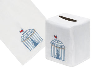 The Beach Cabana Bath Collection by Haute Home features a white Italian linen tissue box cover and towel, beautifully adorned with a hand-embroidered blue cabana design and topped with a charming red flag.