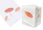 The Beach Umbrella Bath Collection, Coral by Haute Home features white fabric items made from fine Italian linen with red and orange hand-embroidered umbrellas, including a folded piece and a tissue box cover.