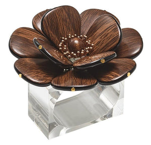 The Begonia Napkin Ring by Kim Seybert features a large, dark brown flower with petal details on a clear rectangular base, adding natural beauty to any table setting.