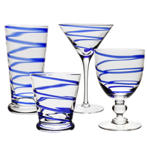 Four vibrant tumblers from the Bella Blue Collection by William Yeoward Crystal, each with unique swirling blue stripes, are displayed against a white background, highlighting modern glass artistry.